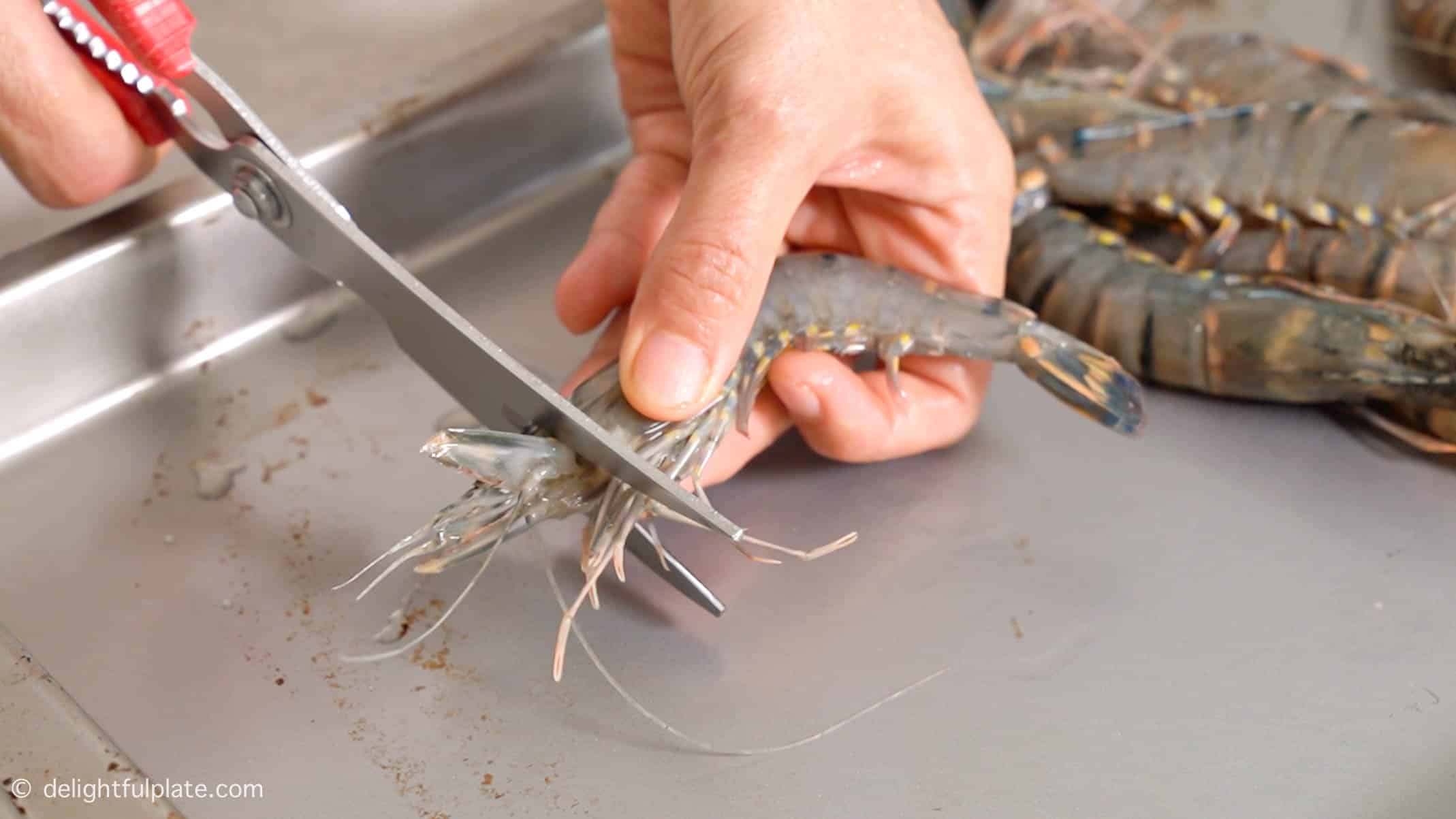 cutting off the top tip of shrimp head with kitchen shears.