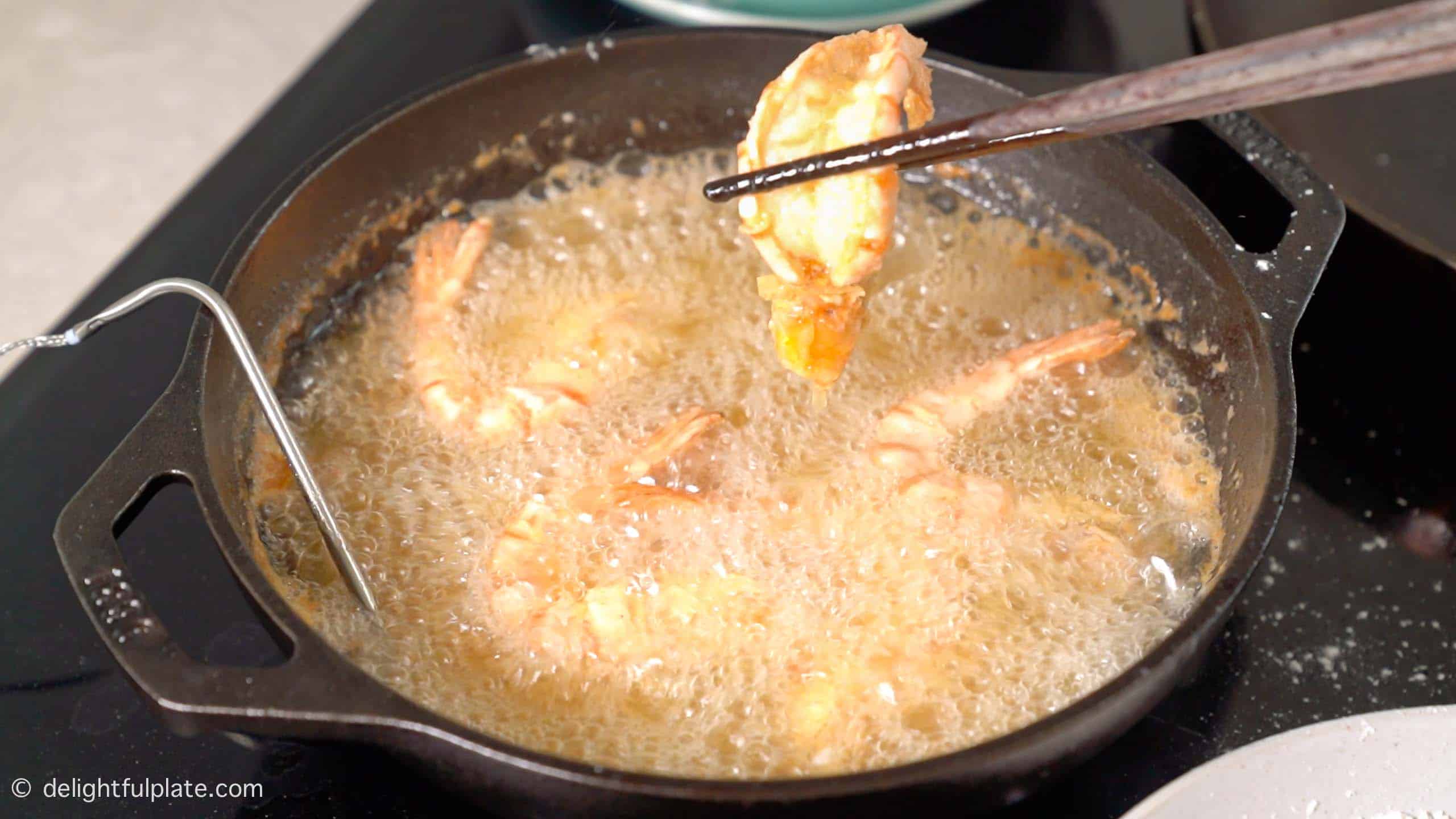 deep frying shrimp in a pan until golden.