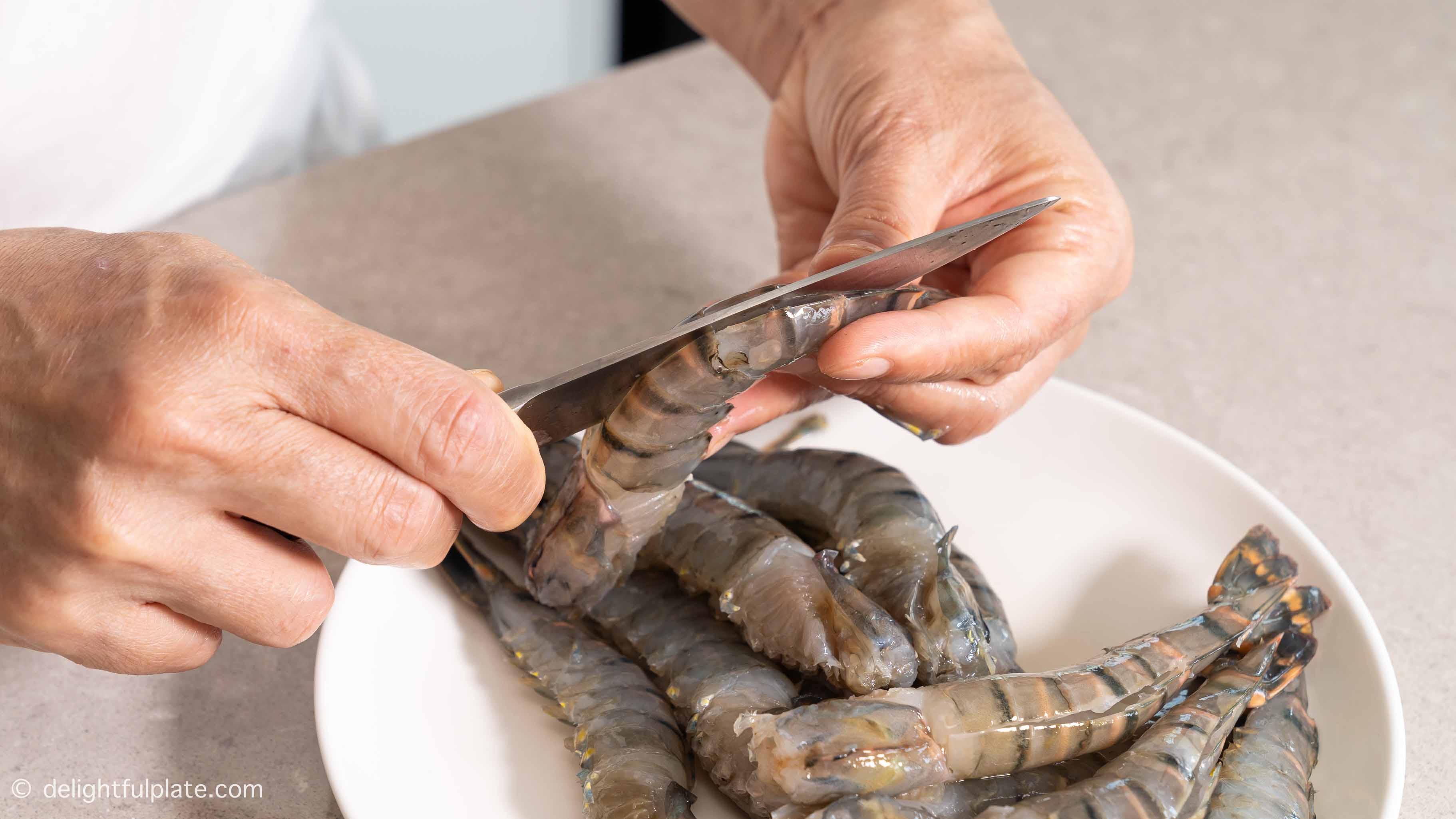 Making a slit down the shrimp back with a paring knife.