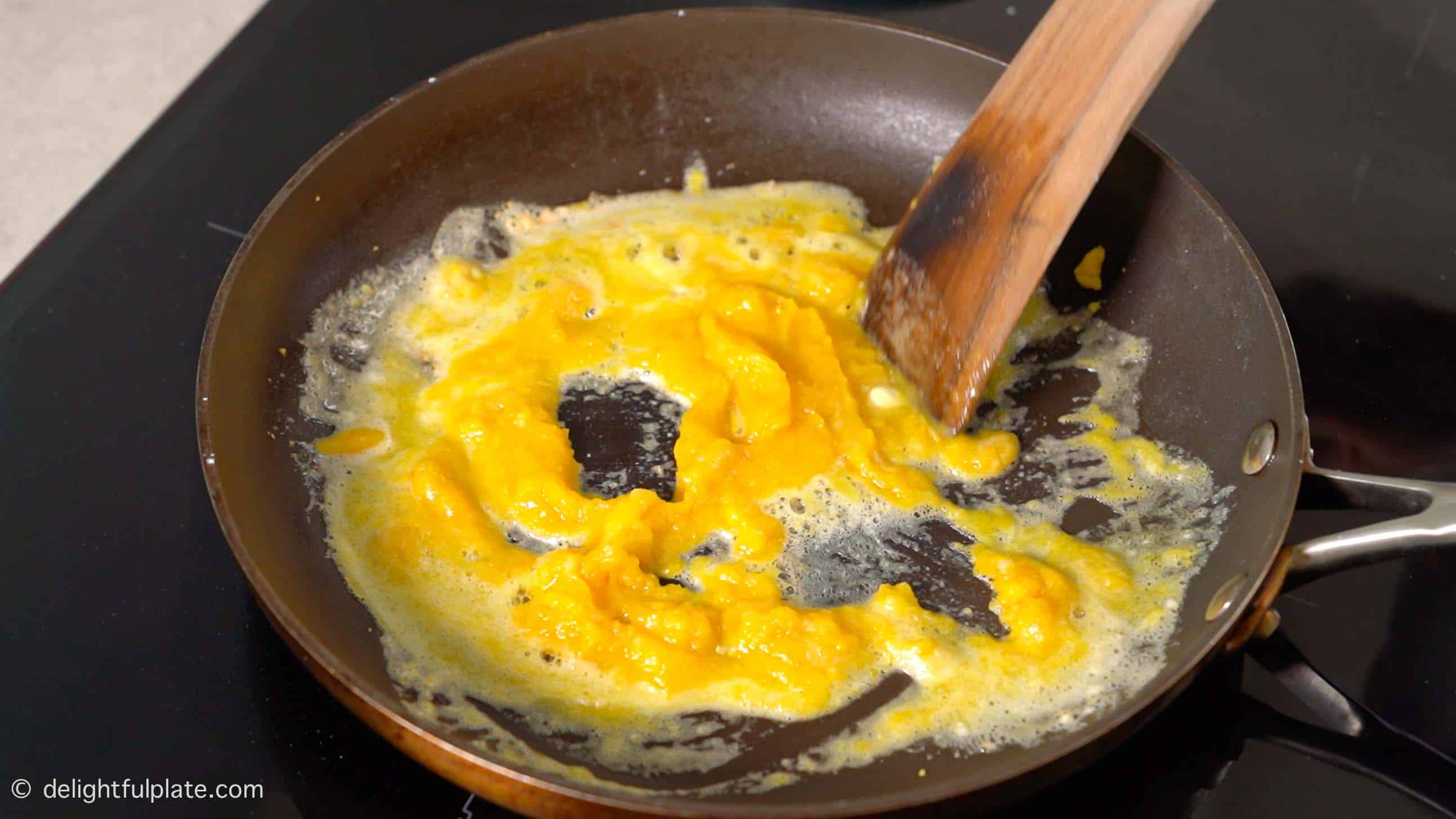 stirring butter in the pan to form a creamy salted egg sauce.