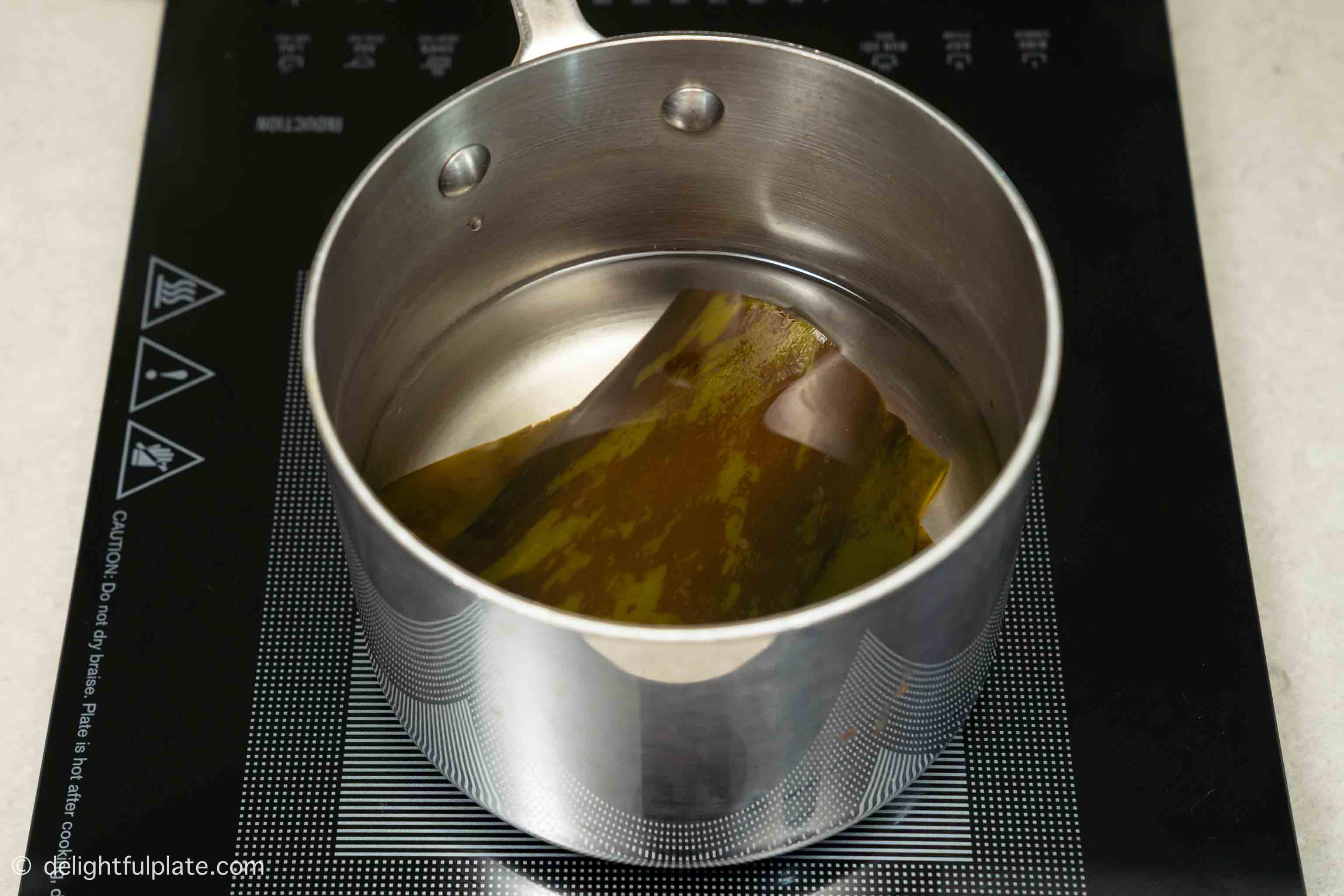 a pot with kombu and water on a cooktop.