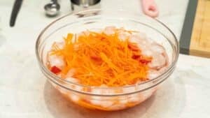 Soaking cut carrot and bell pepper in a bowl of cold water.