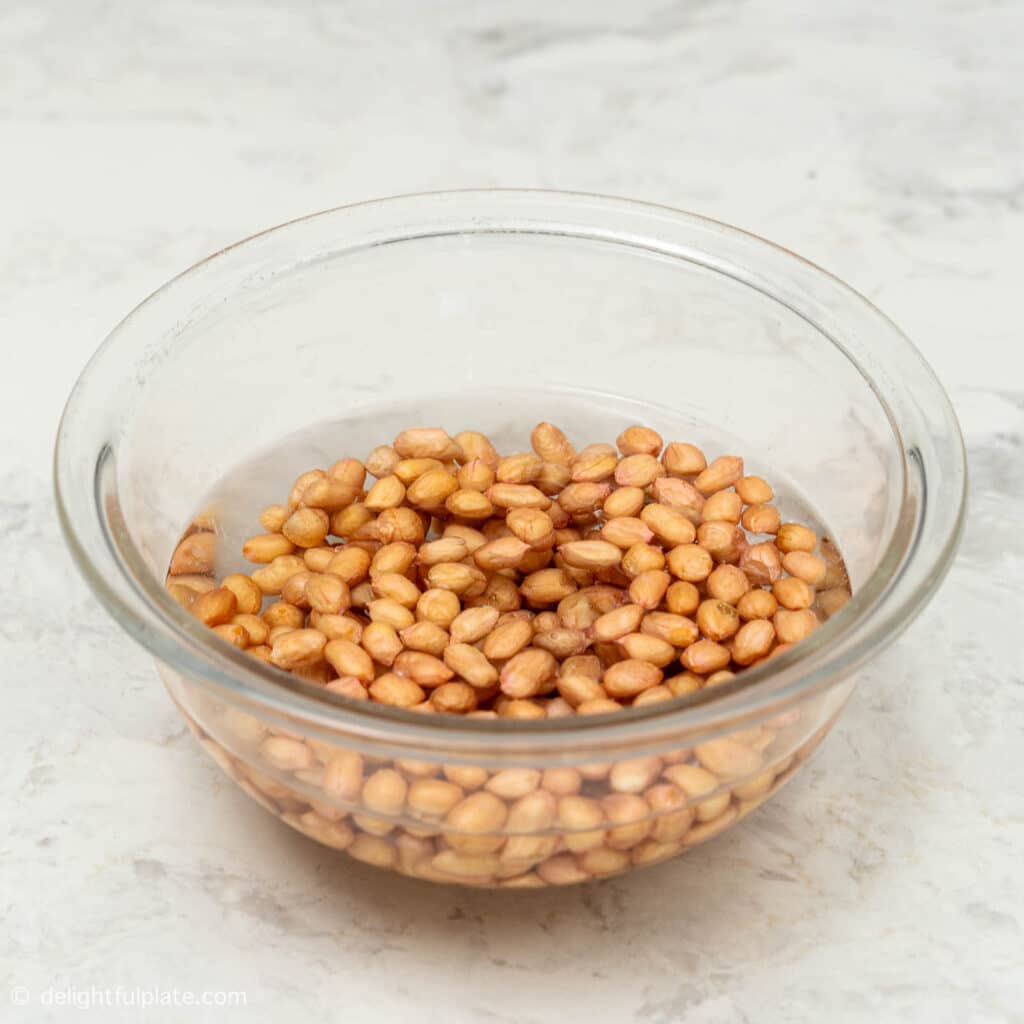 a bowl containing raw peanuts soaked in water.