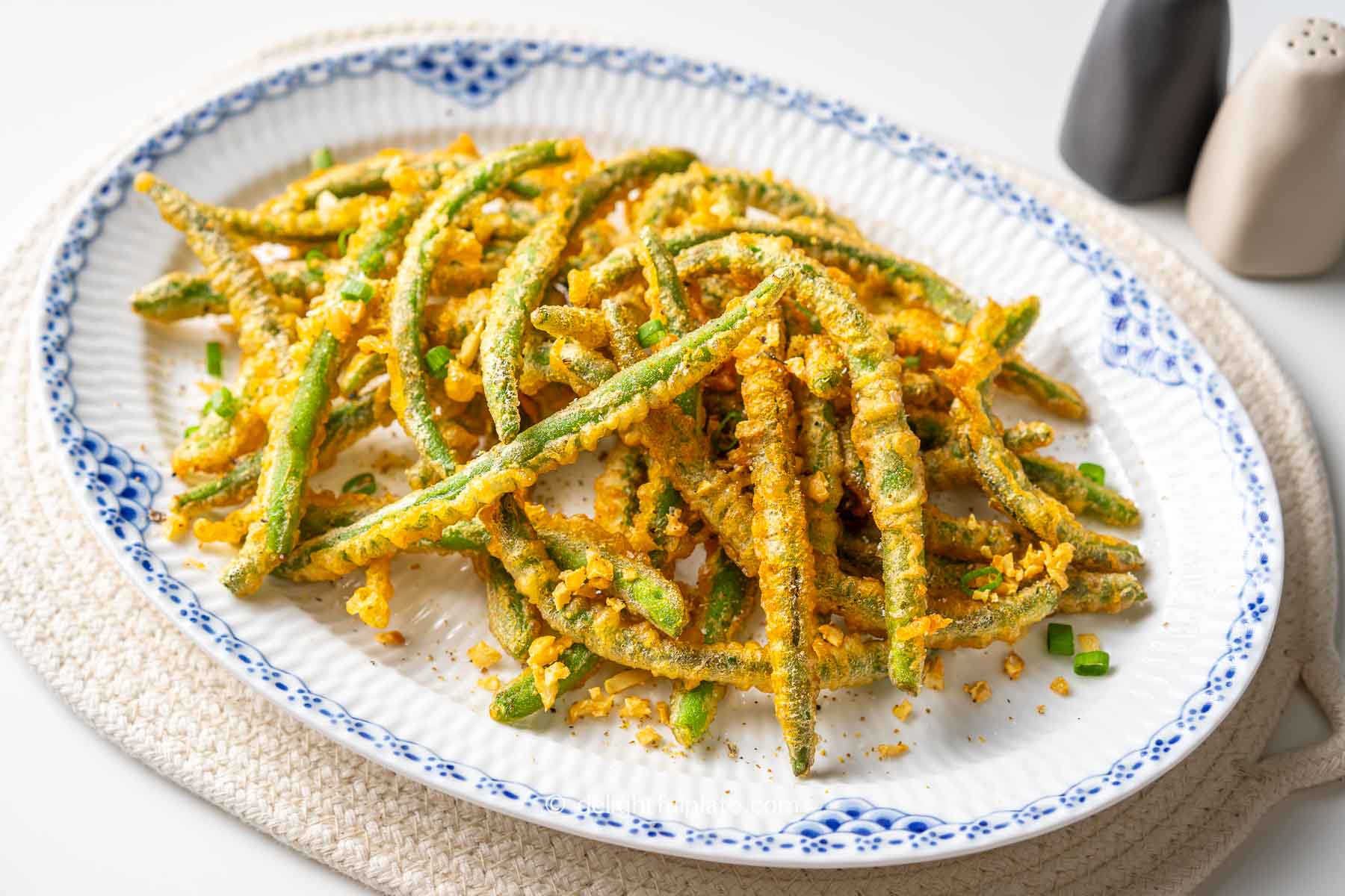 a plate of Golden Fried Green Beans on a white dining table.