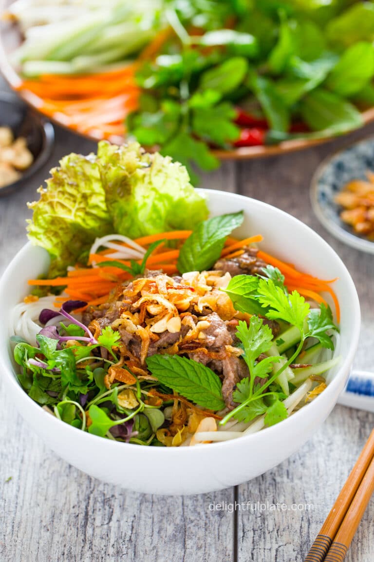 a bowl of bun bo Nam Bo (Vietnamese beef noodle salad) with stir-fried beef and colorful veggies over noodles.