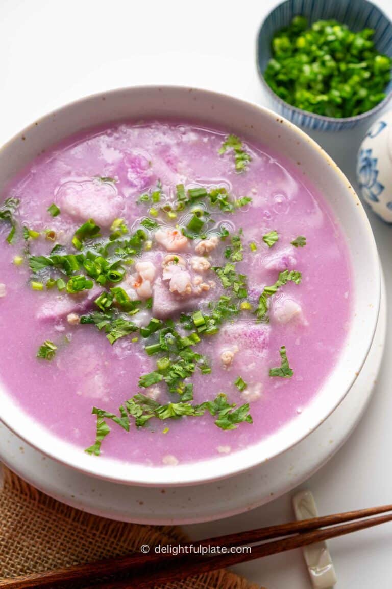 a bowl of canh khoai mỡ (Vietnamese purple yam soup) topped with fresh herbs.