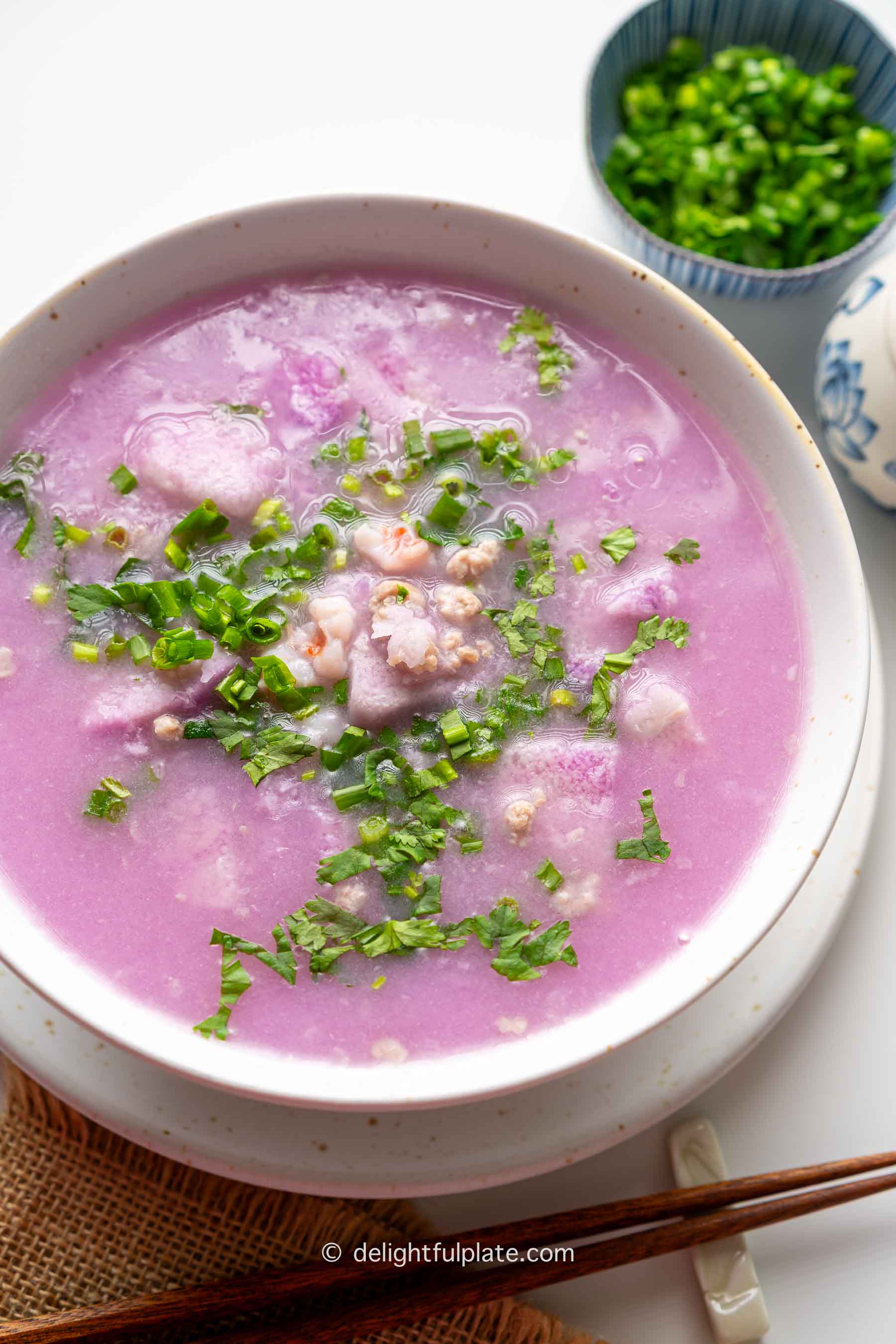 a bowl of canh khoai mỡ (Vietnamese purple yam soup) topped with fresh herbs.
