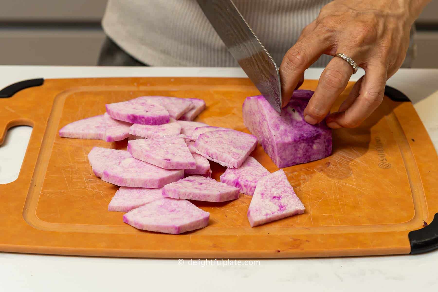 slice purple yam into chunks on a cutting board.