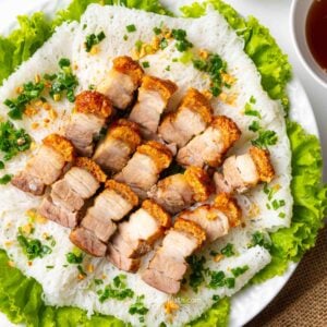 a plate of Vietnamese crispy roast pork belly on a bed of rice vermicelli sheets and lettuce.