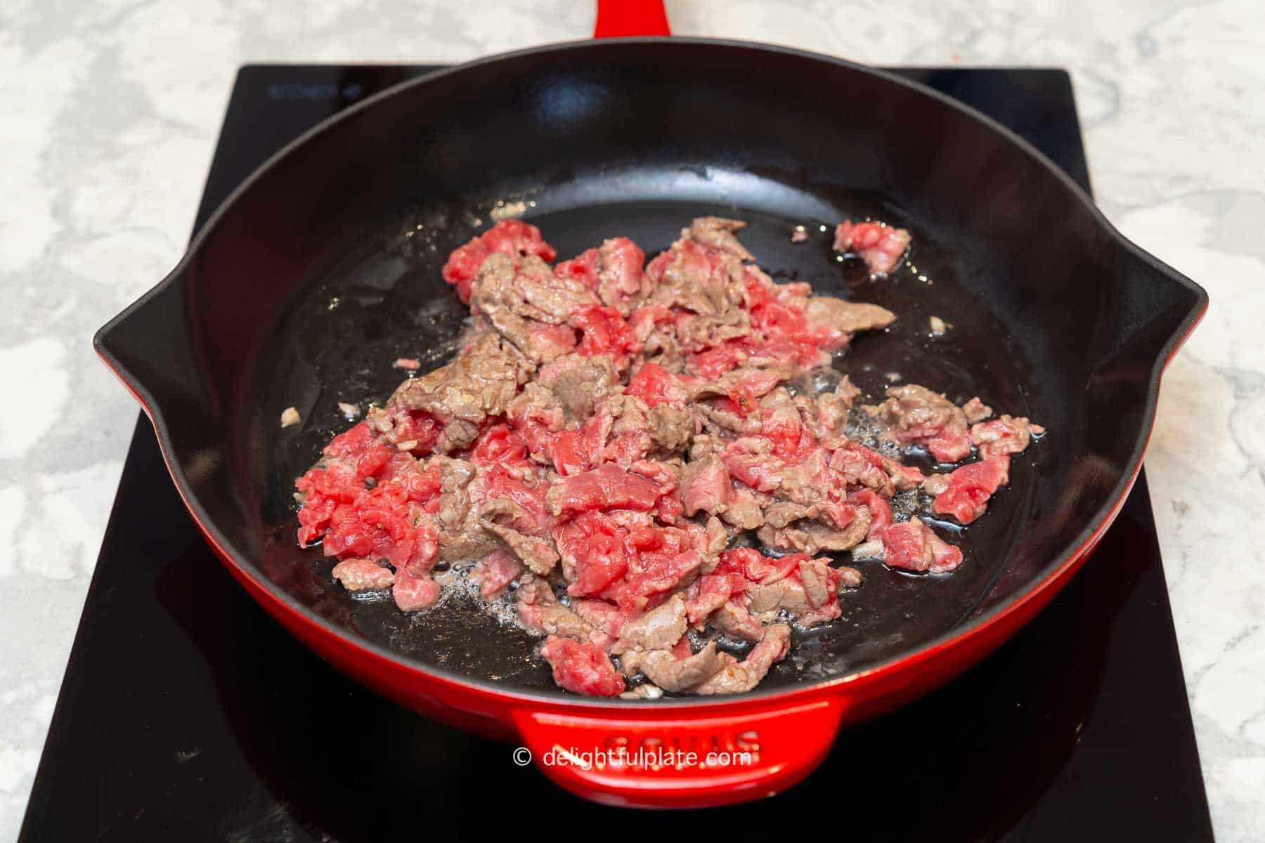 beef slices being cooked in a stir-fry pan.