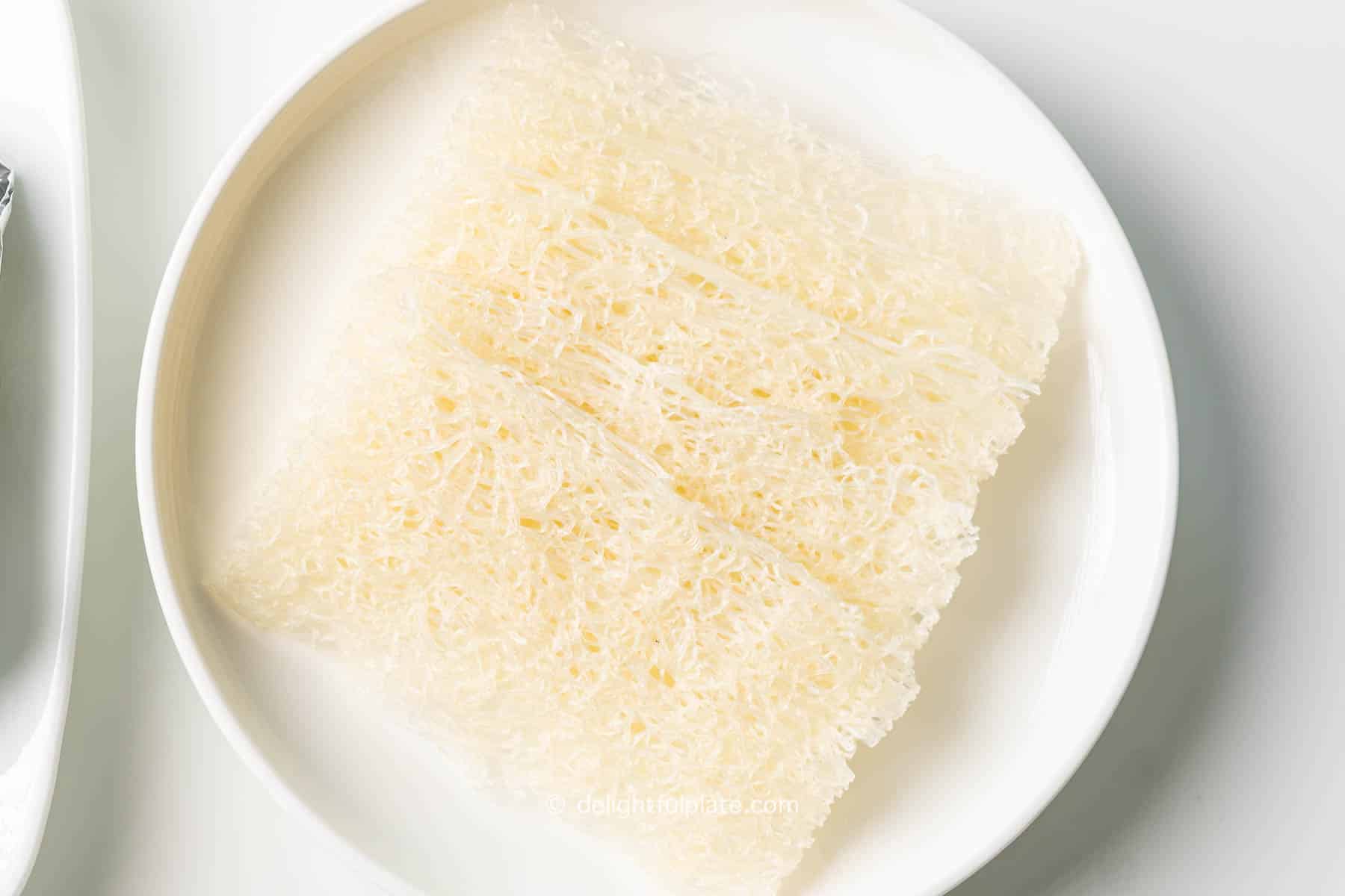 a plate of dried Vietnamese fine rice vermicelli sheets banh hoi.