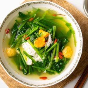 a bowl of spinach soup with salted duck eggs and goji berries.
