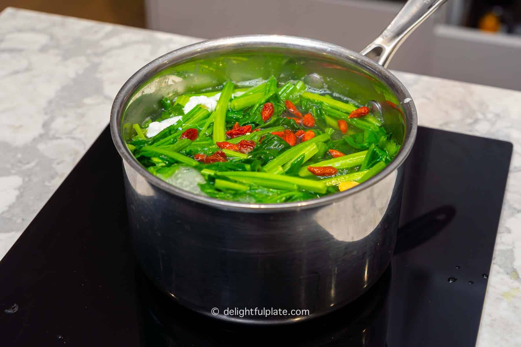 spinach soup being cooked in a pot over stovetop.